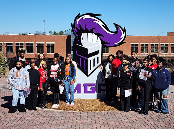 high school students posing my large duke the knight head outside macon campus library